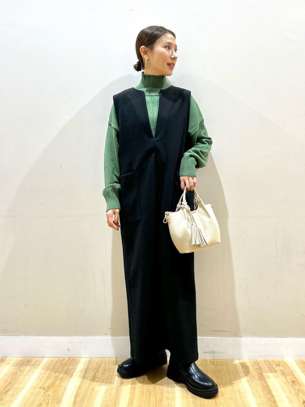 グレー系のその他アウター、グリーン系のニット/セーター、ブラック系のジャンパースカートを着用したレディースの冬コーディネートの5枚目の写真