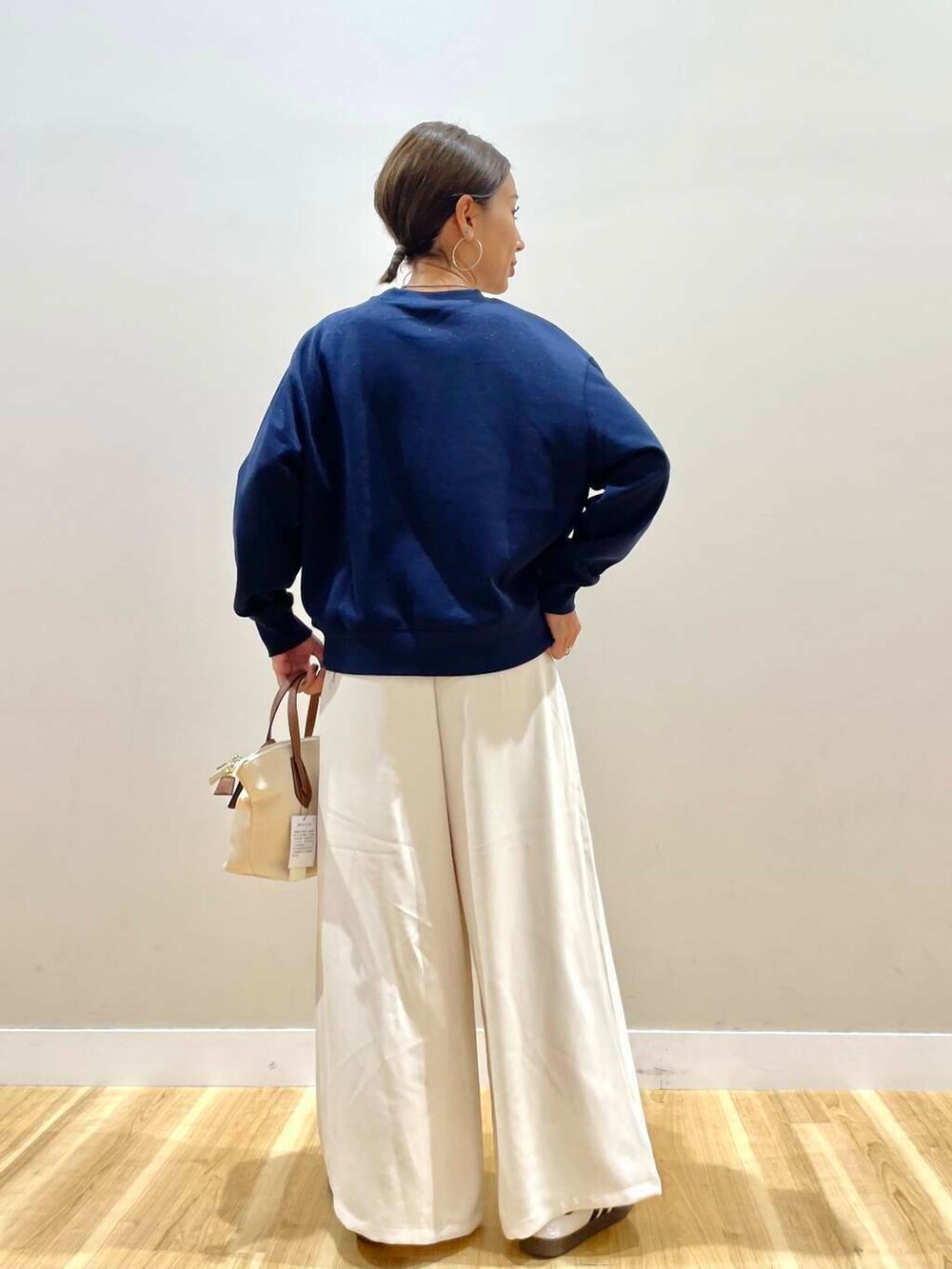 ホワイト系のトートバッグ、ブルー系のスウェット、ホワイト系のスニーカーを着用したレディースの秋コーディネートの4枚目の写真