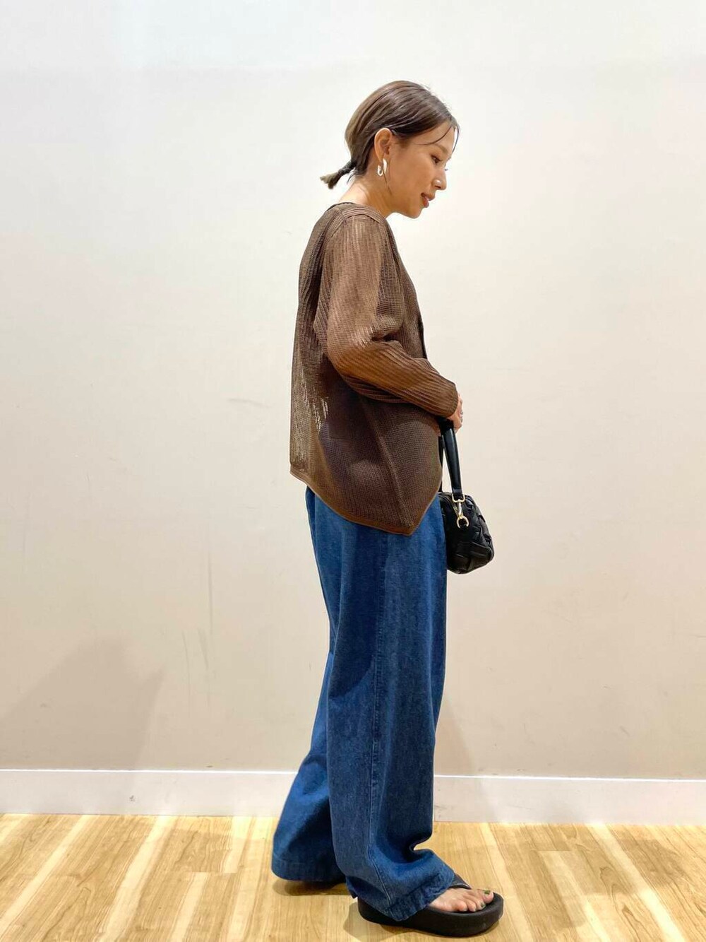 ブラウン系のタンクトップ、ブラック系のショルダーバッグ、ブルー系のデニムパンツを着用したレディースの夏コーディネートの4枚目の写真