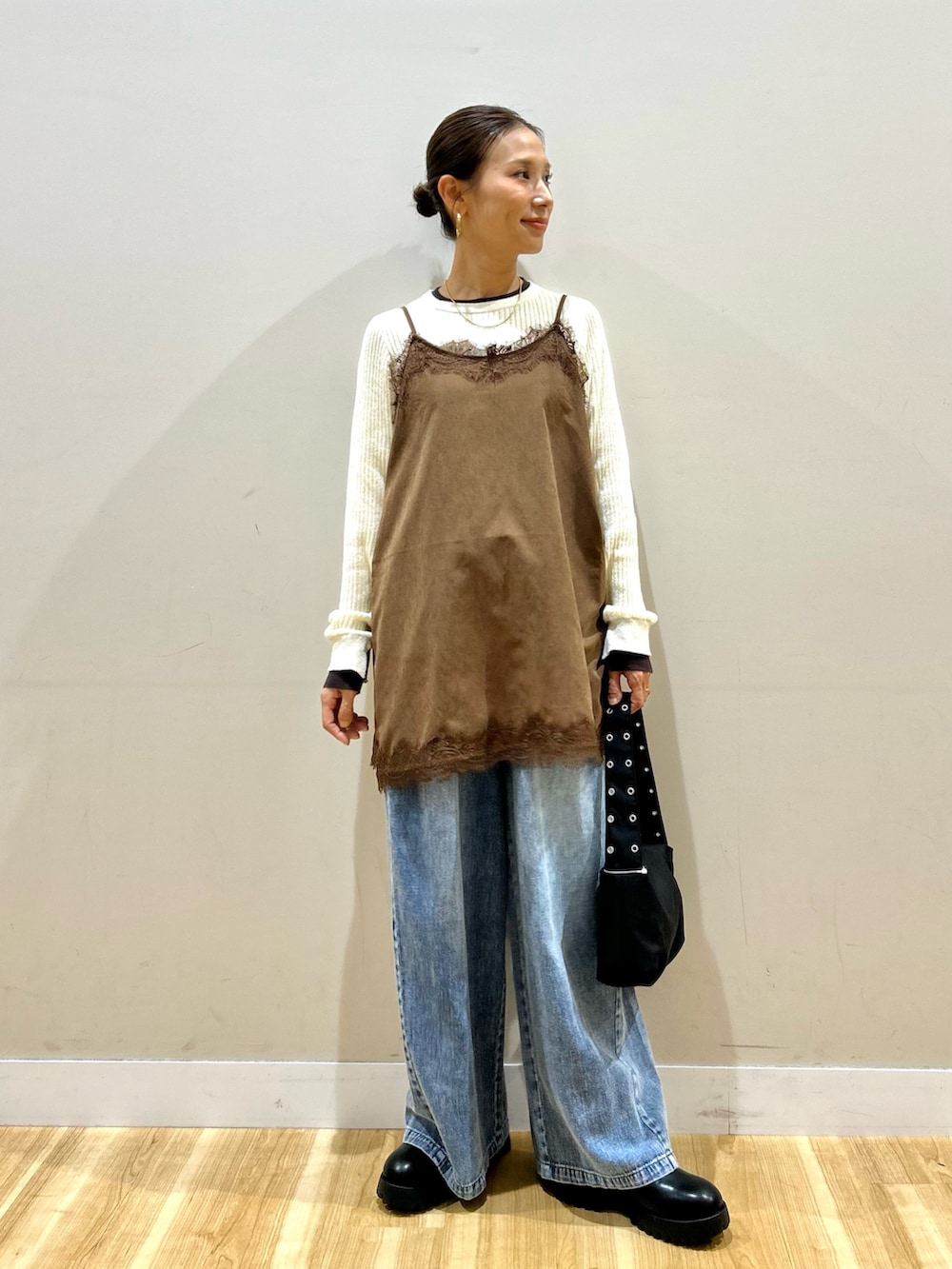 ブルー系のデニムパンツ、ブラック系のショルダーバッグ、ブラック系のブーツを着用したレディースの秋コーディネートの4枚目の写真