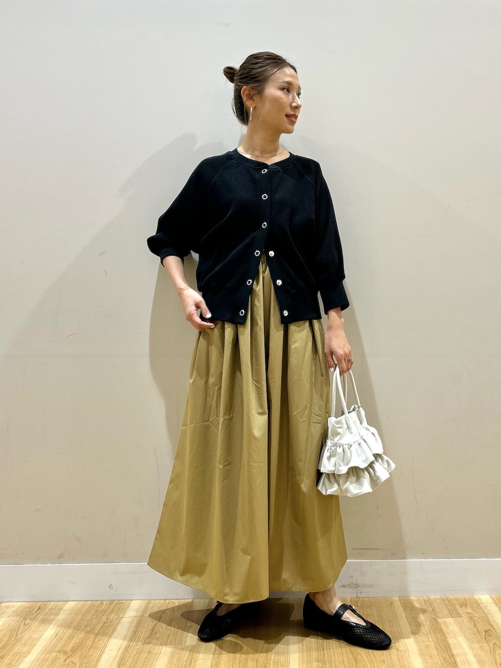 ブラック系のカーディガン/ボレロ、イエロー系のスカート、ホワイト系のハンドバッグを着用したレディースの春コーディネートの4枚目の写真