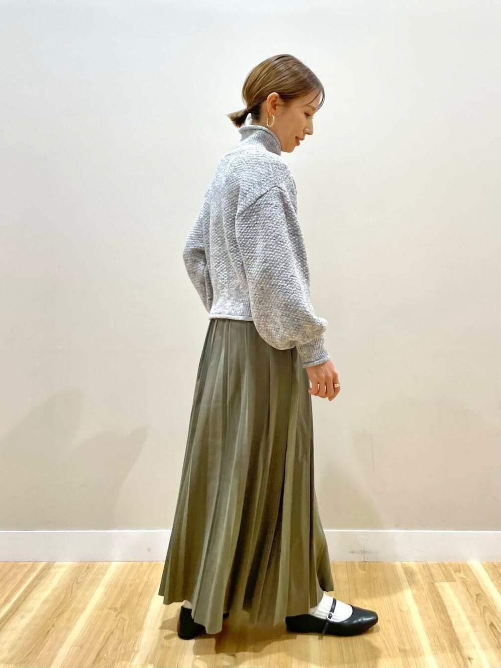 ブラック系のパンプス、グリーン系のスカート、グレー系のハンドバッグを着用したレディースの冬コーディネートの10枚目の写真