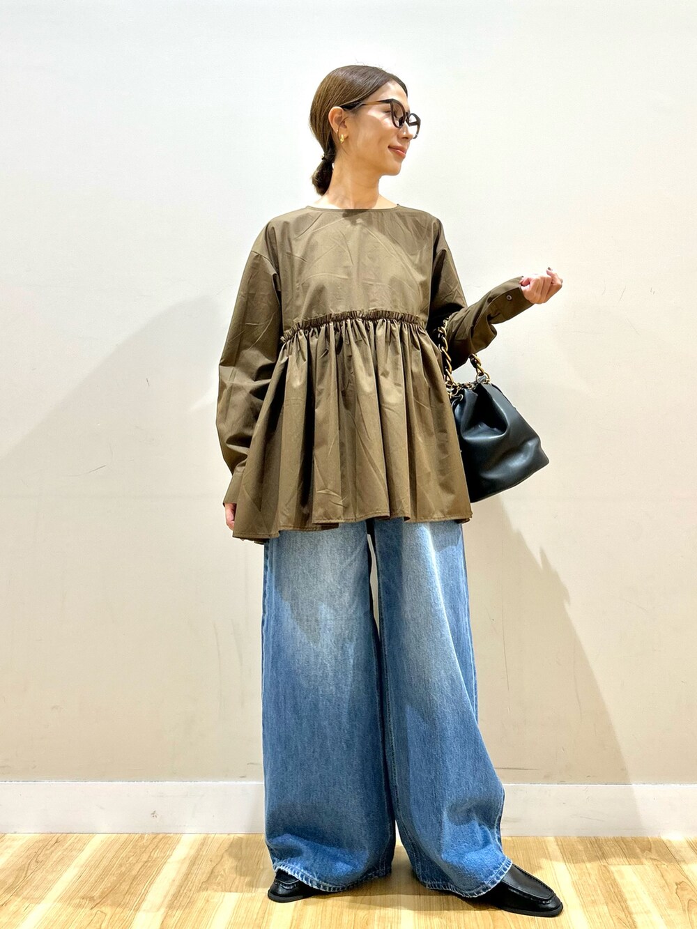 ブラウン系のシャツ/ブラウス、ブルー系のデニムパンツ、ブラック系のショルダーバッグを着用したレディースの秋コーディネートの7枚目の写真