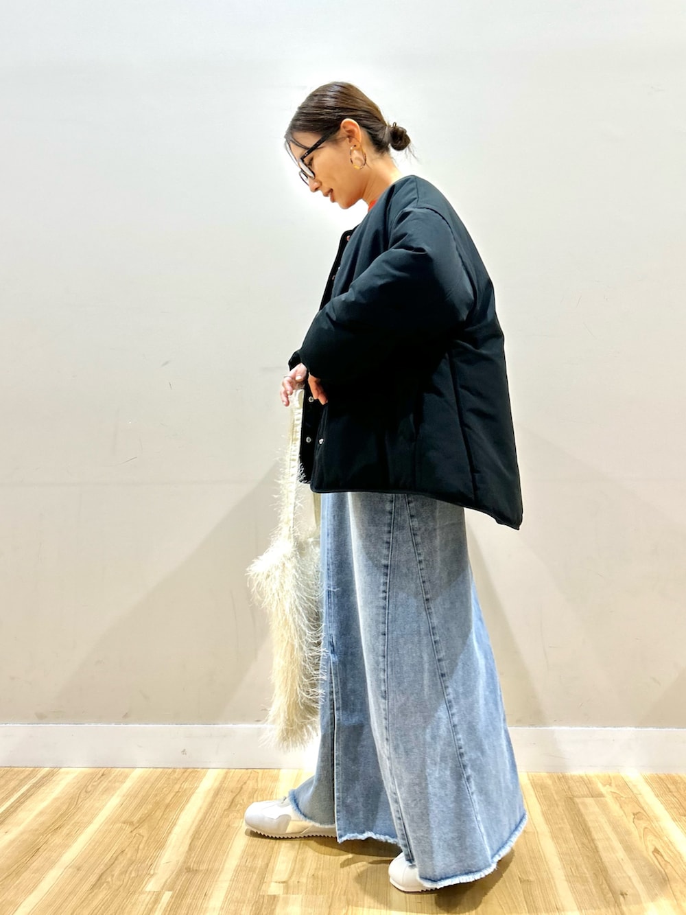 ブラック系のダウンジャケット/コート、オレンジ系のニット/セーター、ブルー系のスカートを着用したレディースの冬コーディネートの4枚目の写真