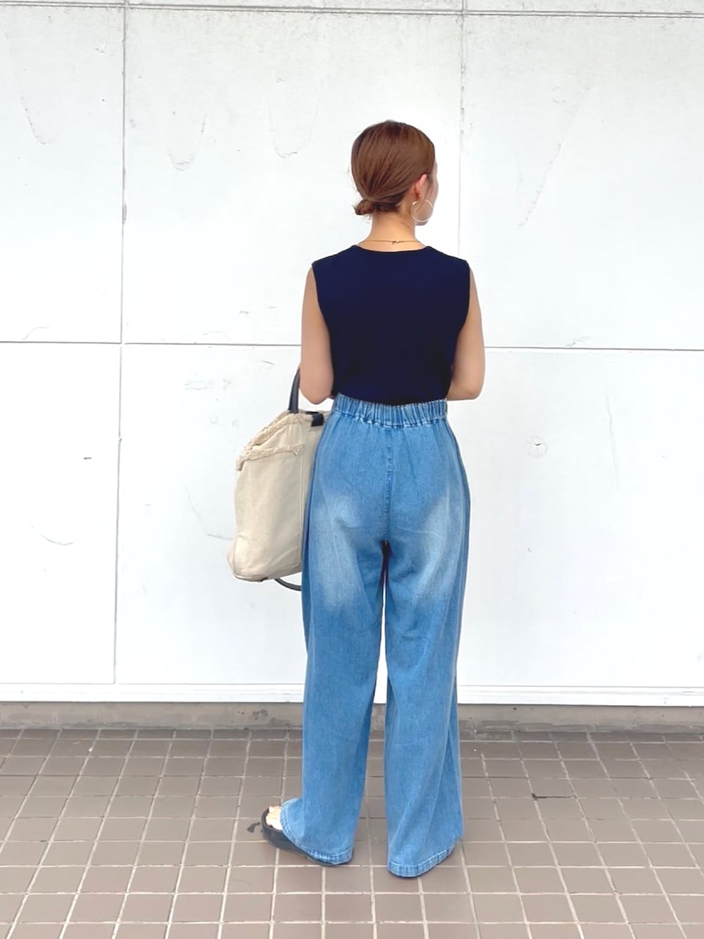 ブルー系のニット/セーター、ブルー系のデニムパンツ、ブラック系のサンダルを着用したレディースの夏コーディネートの3枚目の写真