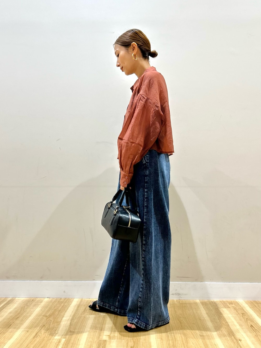 オレンジ系のシャツ/ブラウス、ブルー系のデニムパンツ、ブラック系のハンドバッグを着用したレディースの夏コーディネートの2枚目の写真