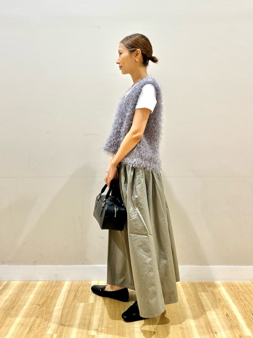 グレー系のベスト、ホワイト系のTシャツ/カットソー、グリーン系のスカートを着用したレディースの夏コーディネートの2枚目の写真