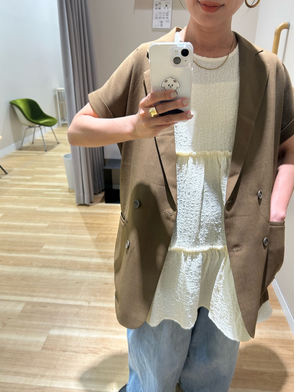 ブラウン系のダウンベスト、ホワイト系のチュニックを着用したレディースの春コーディネートの2枚目の写真