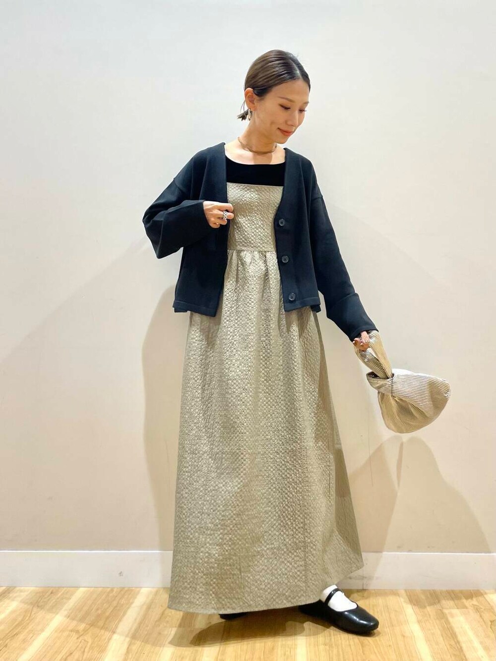 ブラック系のパンプス、ゴールド系のハンドバッグ、ブラック系のタンクトップを着用したレディースの秋コーディネートの2枚目の写真