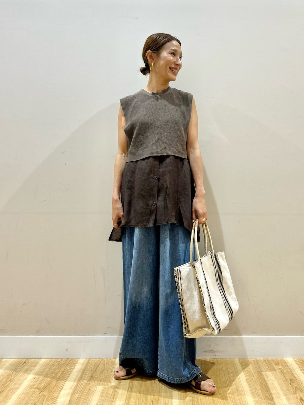 ブラウン系のシャツ/ブラウス、ブルー系のデニムパンツ、ホワイト系のトートバッグを着用したレディースの夏コーディネートの2枚目の写真