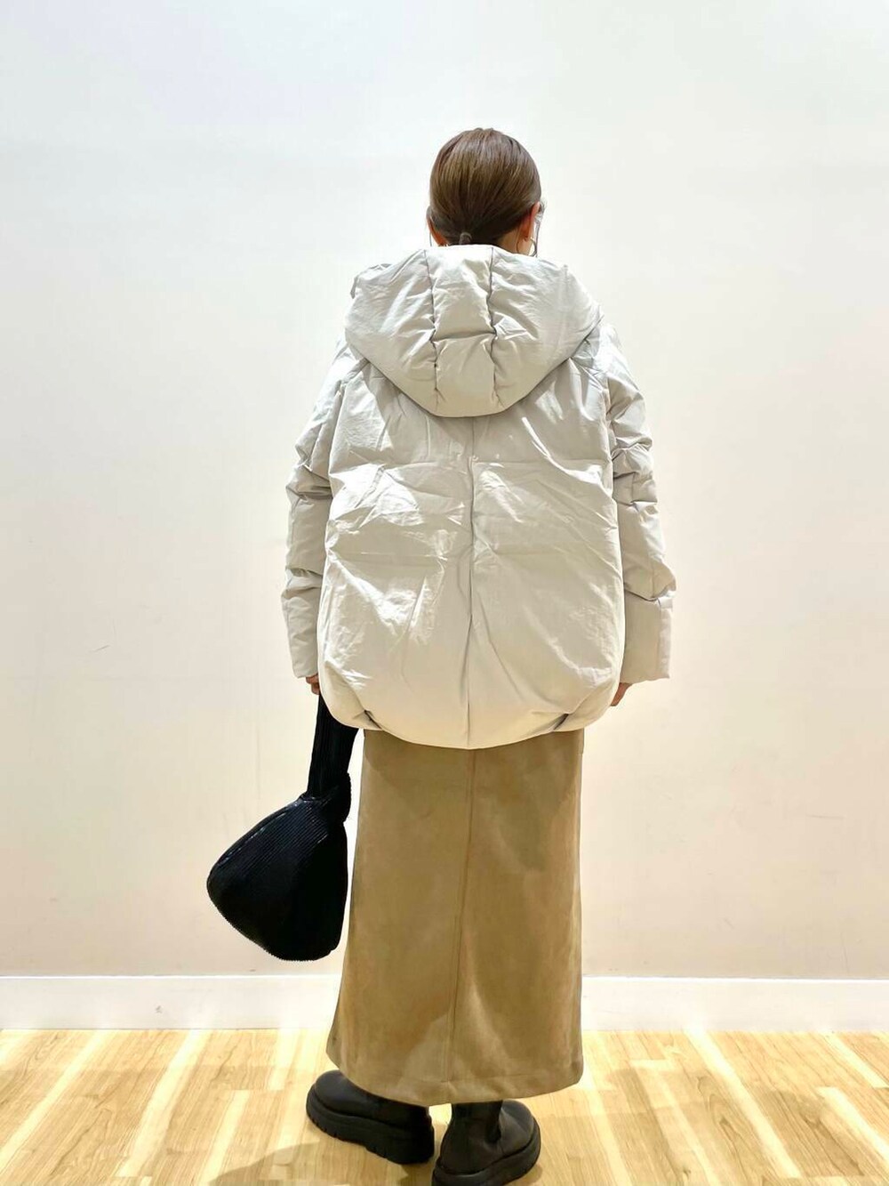 ブラウン系のスカート、ブラック系のハンドバッグ、グレー系のニット/セーターを着用したレディースの冬コーディネートの3枚目の写真