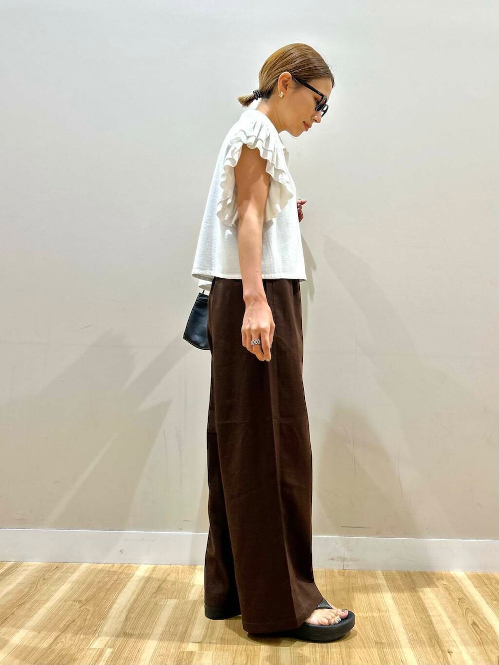 ブラウン系のその他パンツ、ブラック系のサンダル、ブラック系のハンドバッグを着用したレディースの夏コーディネートの4枚目の写真