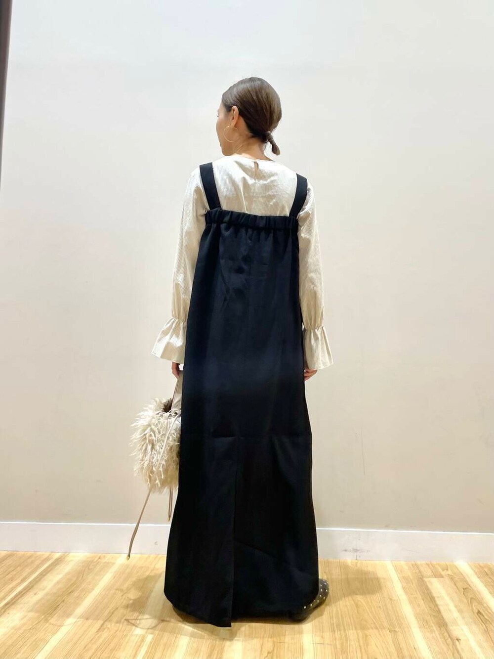 ベージュ系のショルダーバッグ、ブラック系のパンプス、ブラック系のジャンパースカートを着用したレディースの秋コーディネートの3枚目の写真