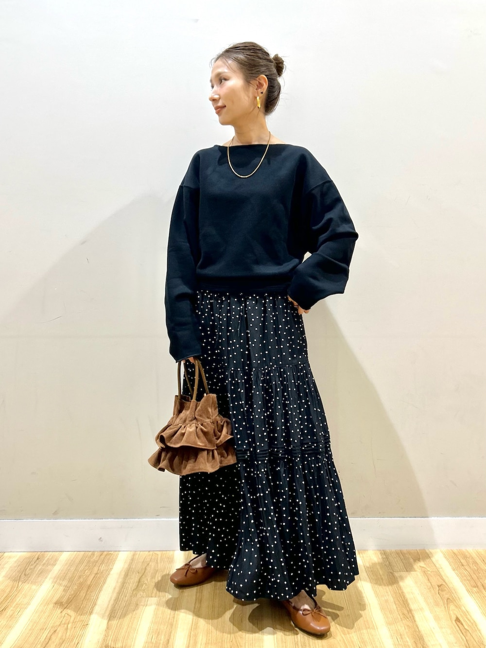 ブラック系のスウェット、ブラック系のスカート、ブラウン系のハンドバッグを着用したレディースの春コーディネートの4枚目の写真