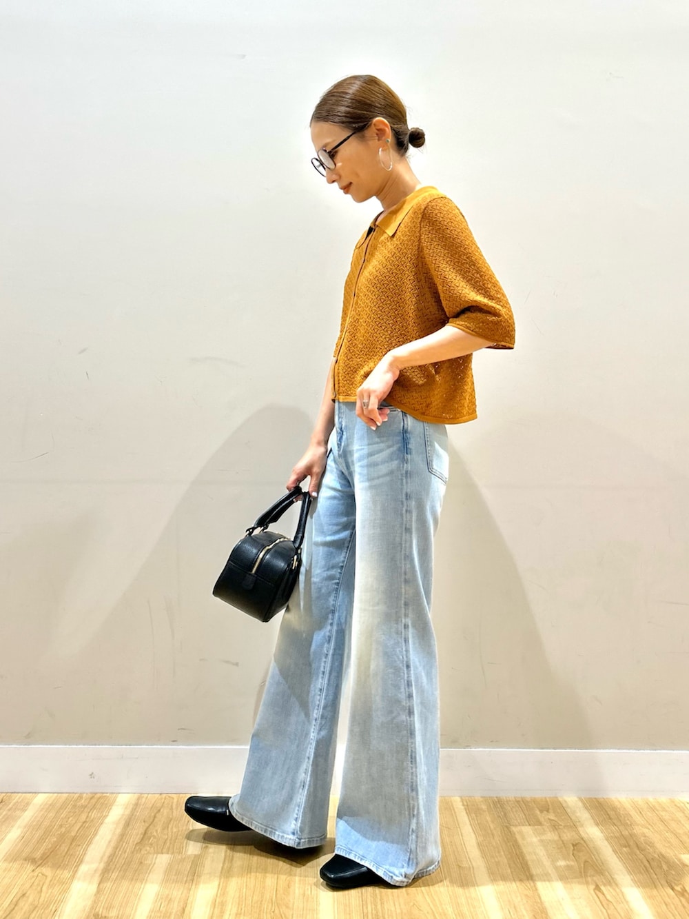 ブラウン系のニット/セーター、ブルー系のデニムパンツ、ブラック系のハンドバッグを着用したレディースの夏コーディネートの3枚目の写真