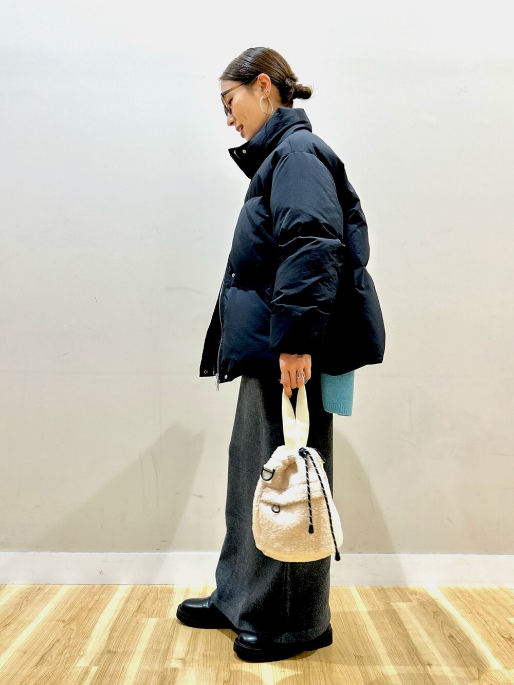 ブラック系のダウンジャケット/コート、ブルー系のニット/セーター、グレー系のスカートを着用したレディースの冬コーディネートの4枚目の写真