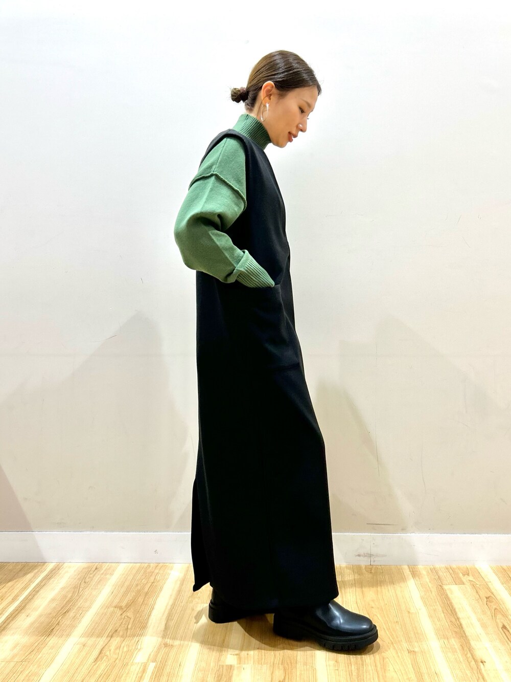 グレー系のその他アウター、グリーン系のニット/セーター、ブラック系のジャンパースカートを着用したレディースの冬コーディネートの6枚目の写真