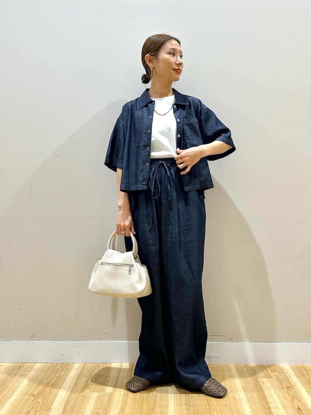 ホワイト系のTシャツ/カットソー、ブルー系のデニムパンツ、ブラウン系のハンドバッグを着用したレディースの春コーディネートの4枚目の写真