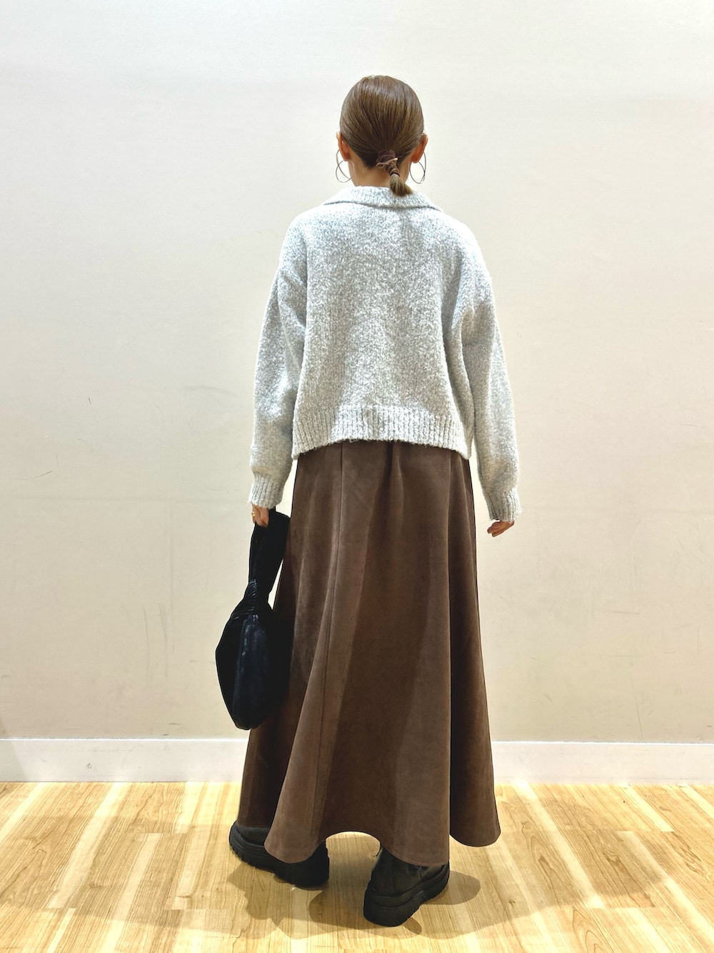 ブラック系のダウンジャケット/コート、グレー系のニット/セーター、ブラウン系のスカートを着用したレディースの秋コーディネートの6枚目の写真