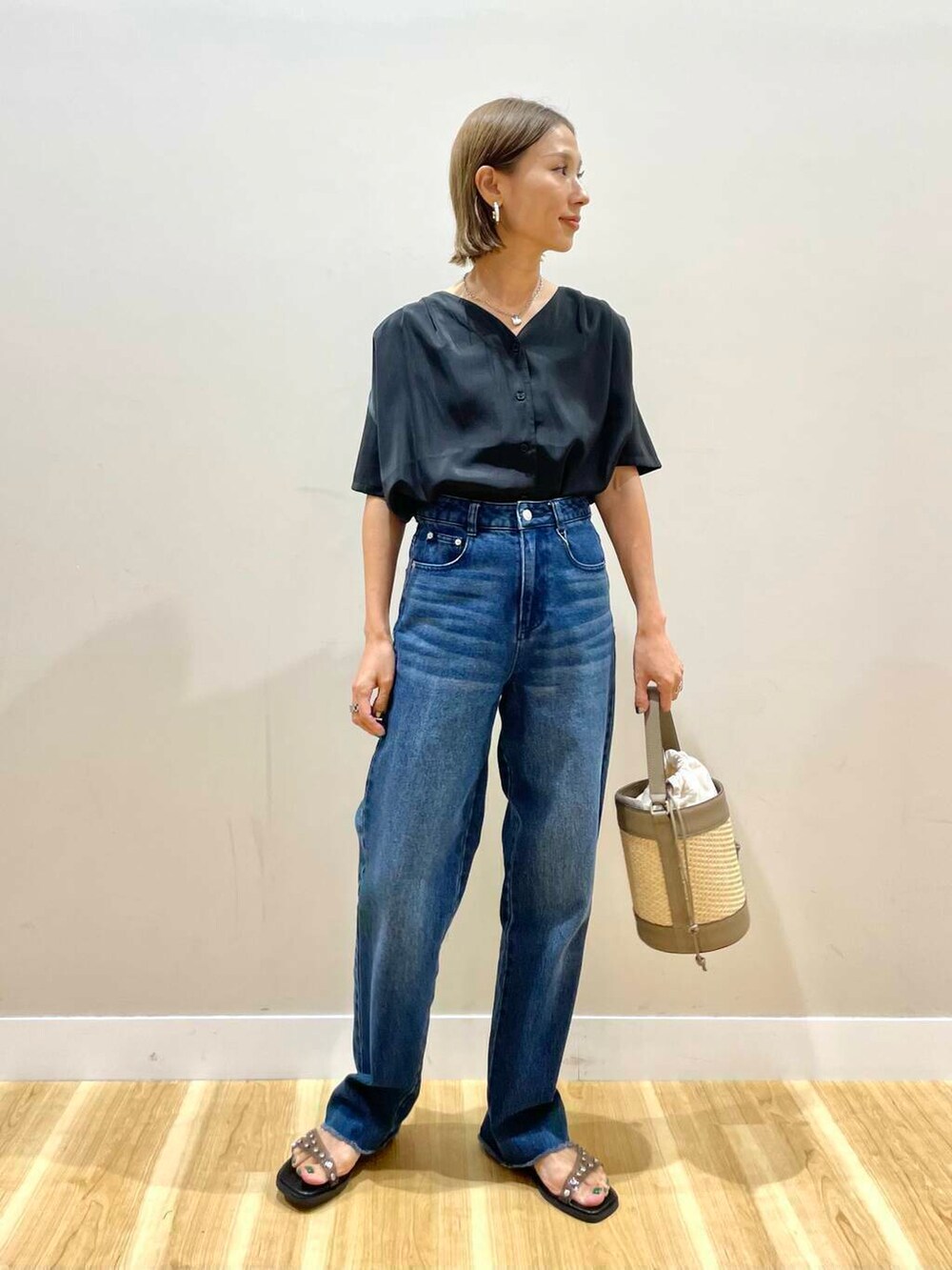 グレー系のショルダーバッグ、ブラック系のサンダル、ブルー系のデニムパンツを着用したレディースの夏コーディネートの2枚目の写真