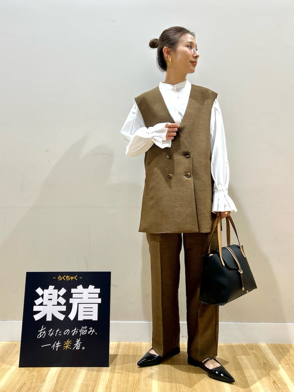 ブラウン系のセットアップ、ホワイト系のシャツ/ブラウス、ブラック系のトートバッグを着用したレディースの春コーディネートの4枚目の写真
