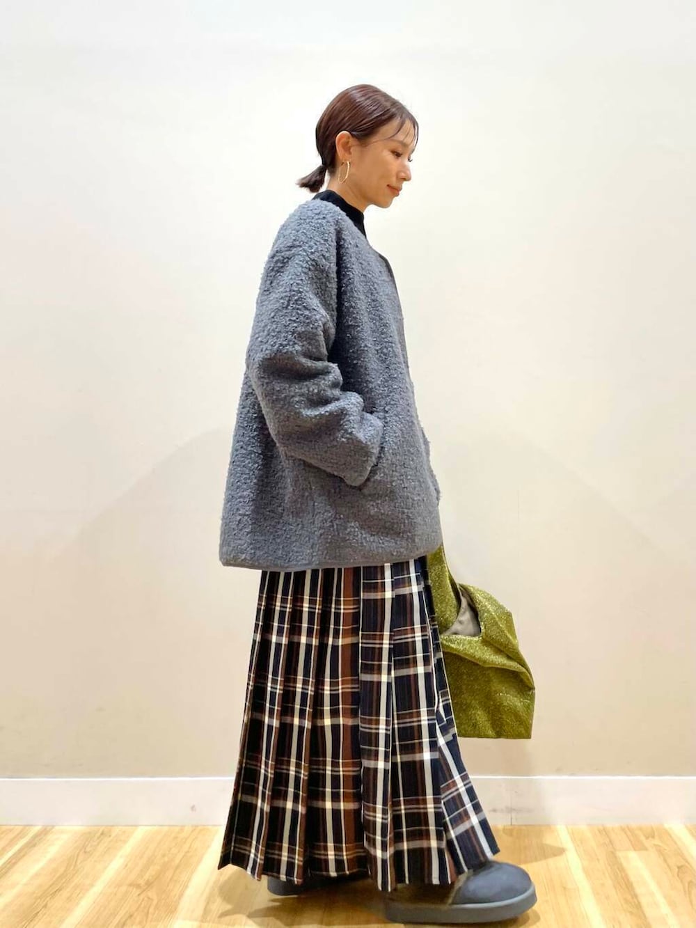 ゴールド系のトートバッグ、ブラック系のニット/セーター、ブルー系のスカートを着用したレディースの冬コーディネートの3枚目の写真