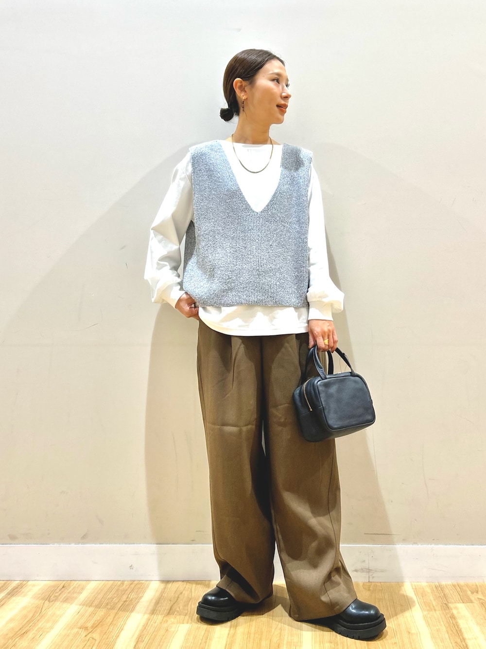 グレー系のベスト、ブラウン系のその他パンツ、ブラック系のボストンバッグを着用したレディースの冬コーディネートの5枚目の写真