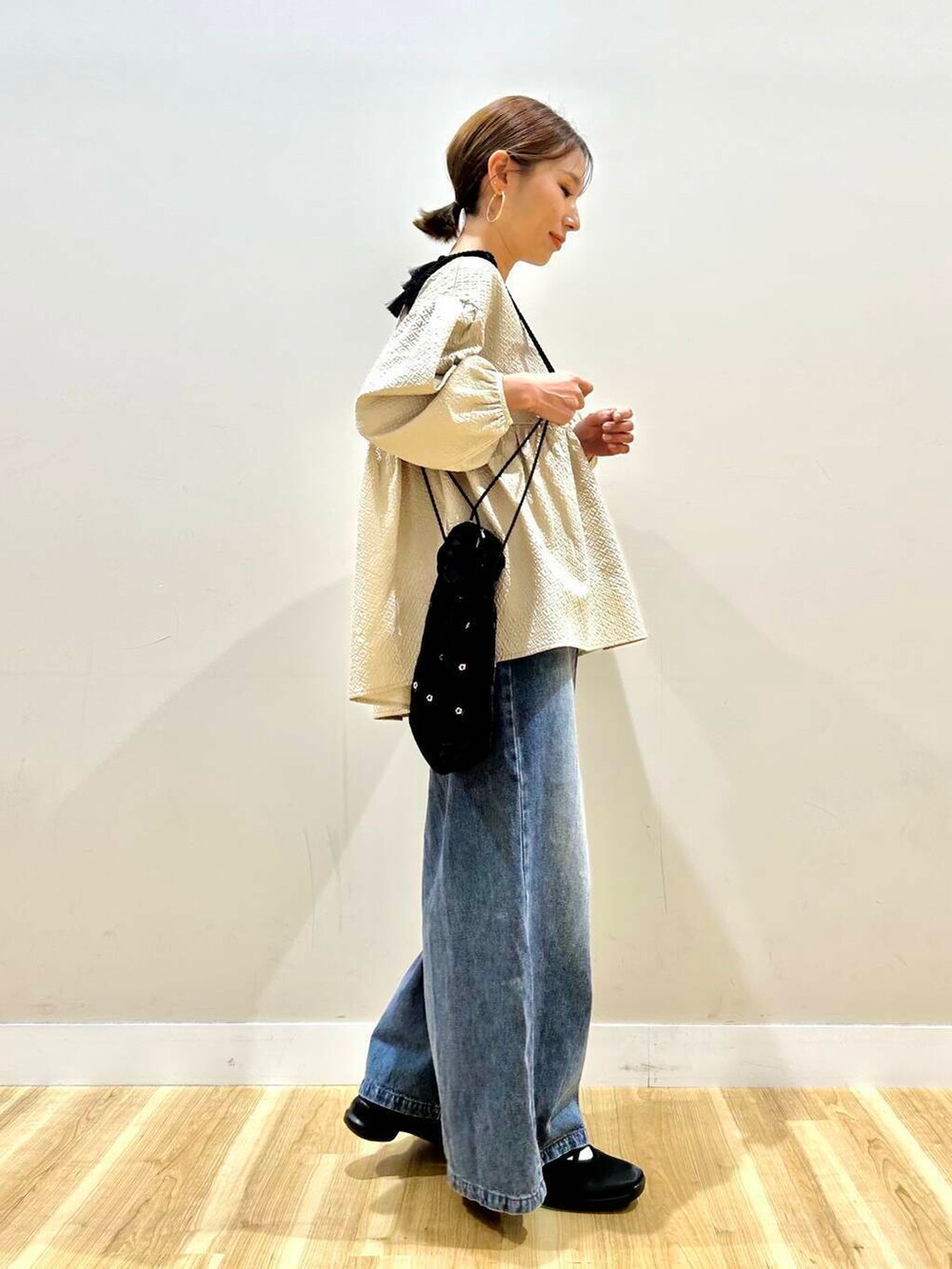 ブラック系のショルダーバッグ、ブルー系のデニムパンツ、ベージュ系のシャツ/ブラウスを着用したレディースの春コーディネートの3枚目の写真