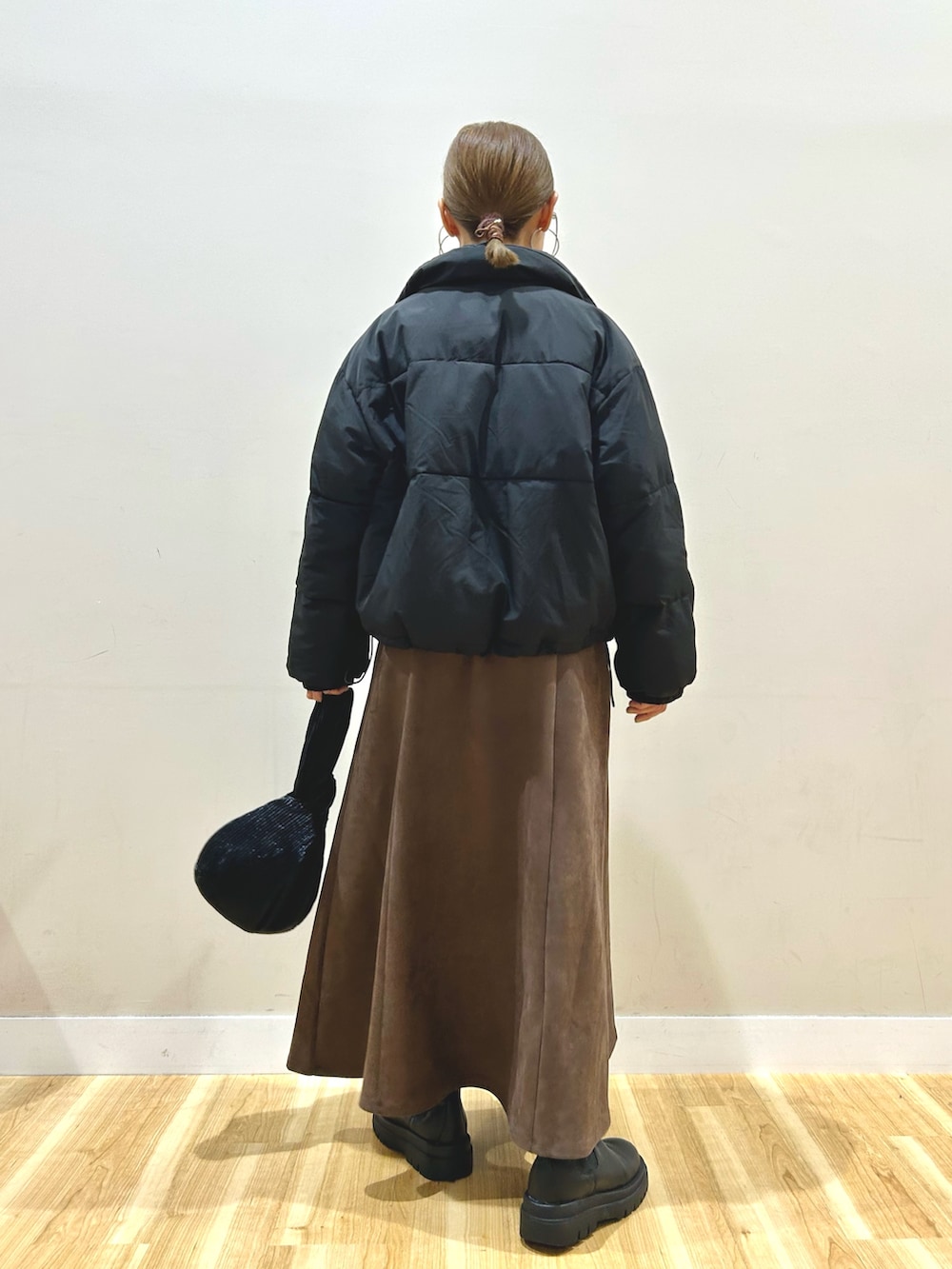 ブラック系のダウンジャケット/コート、グレー系のニット/セーター、ブラウン系のスカートを着用したレディースの秋コーディネートの3枚目の写真