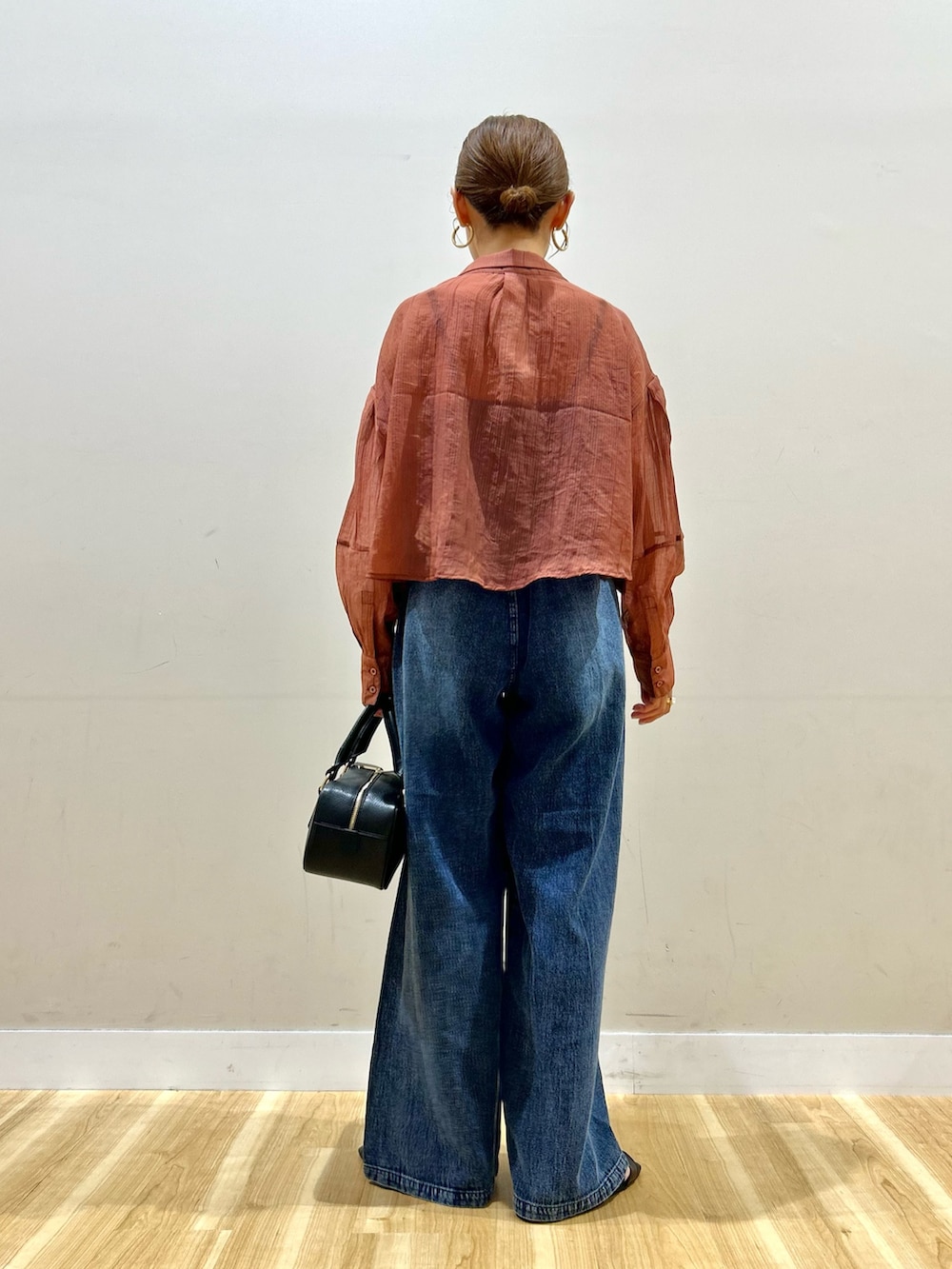 オレンジ系のシャツ/ブラウス、ブルー系のデニムパンツ、ブラック系のハンドバッグを着用したレディースの夏コーディネートの3枚目の写真