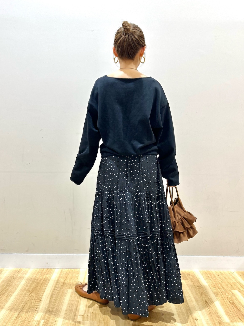 ブラック系のスウェット、ブラック系のスカート、ブラウン系のハンドバッグを着用したレディースの春コーディネートの6枚目の写真