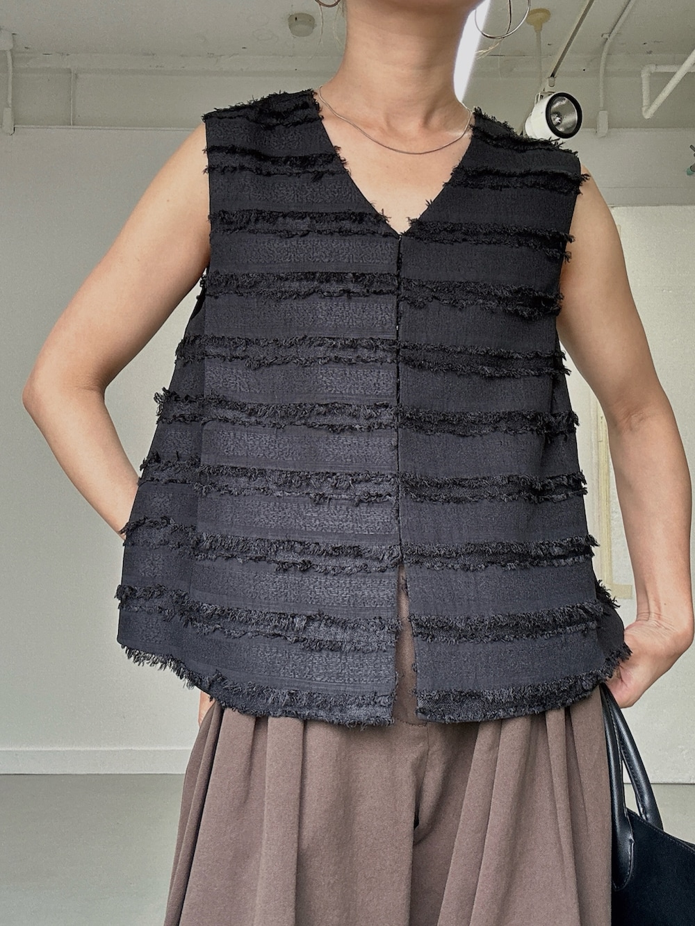 ブラック系のベスト、ブラウン系のその他パンツ、ブラック系のサンダルを着用したレディースの春コーディネートの5枚目の写真