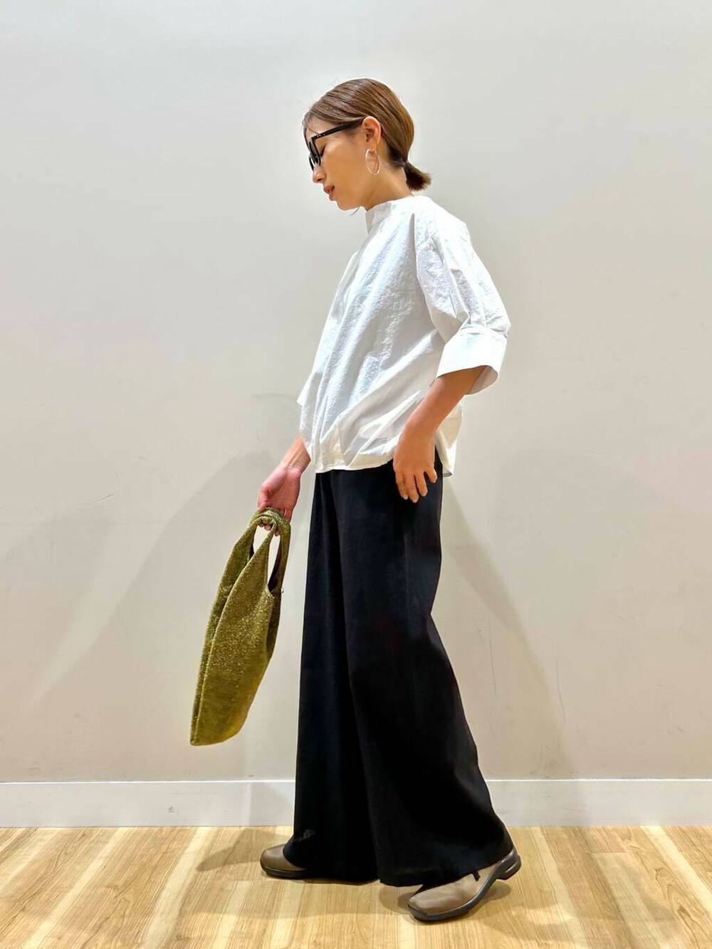 ゴールド系のトートバッグ、ブラック系のその他パンツ、ホワイト系のシャツ/ブラウスを着用したレディースの春コーディネートの2枚目の写真