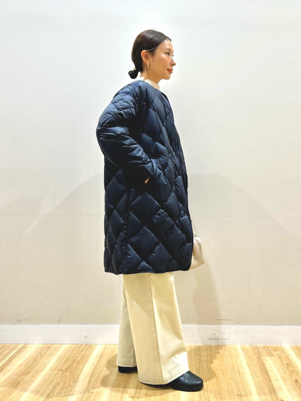 ブルー系のダウンジャケット/コート、ホワイト系のニット/セーター、ベージュ系のその他パンツを着用したレディースの冬コーディネートの2枚目の写真