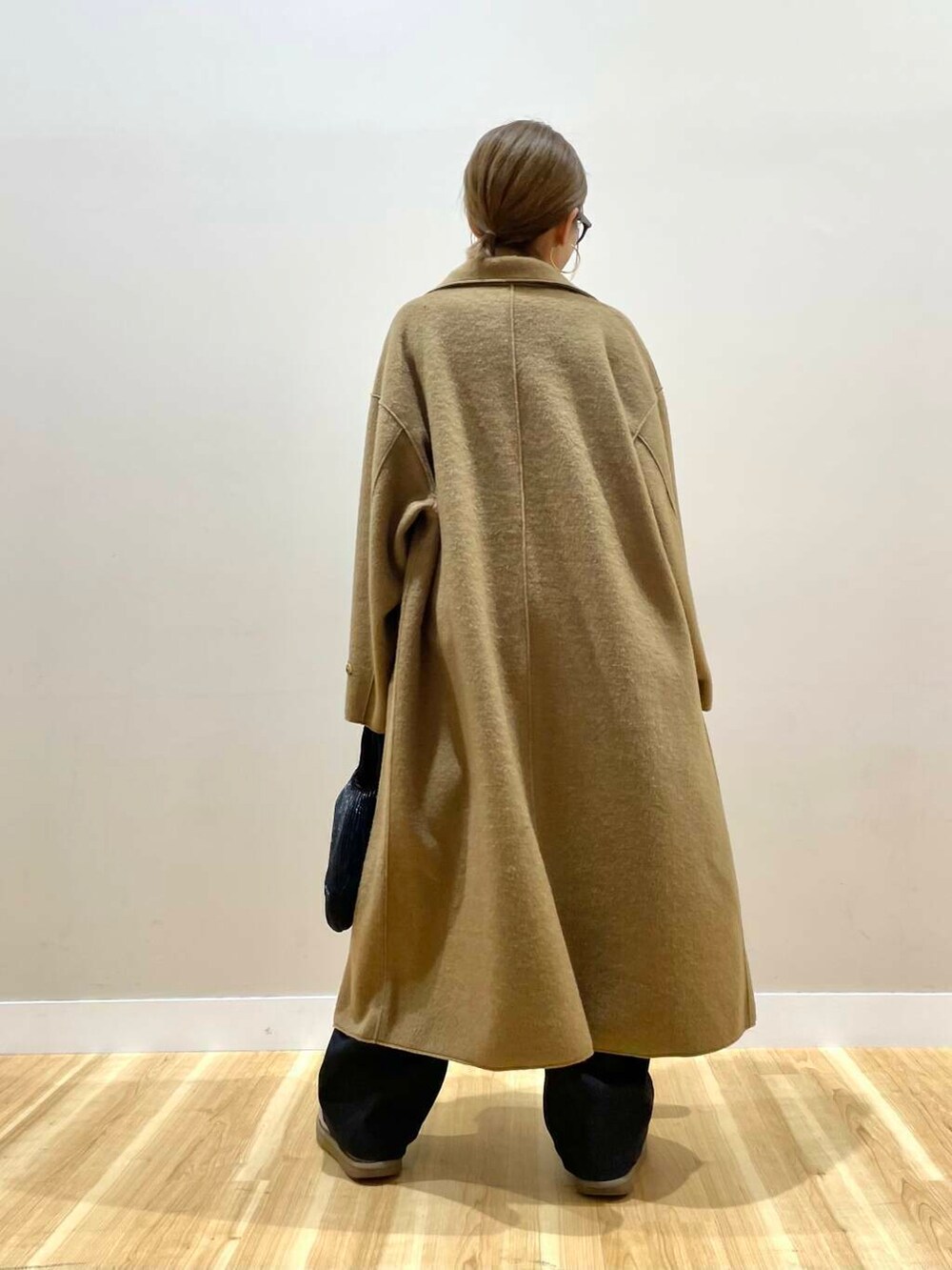 ブラック系のハンドバッグ、ブラック系のニット/セーター、ブラック系のデニムパンツを着用したレディースの秋コーディネートの5枚目の写真