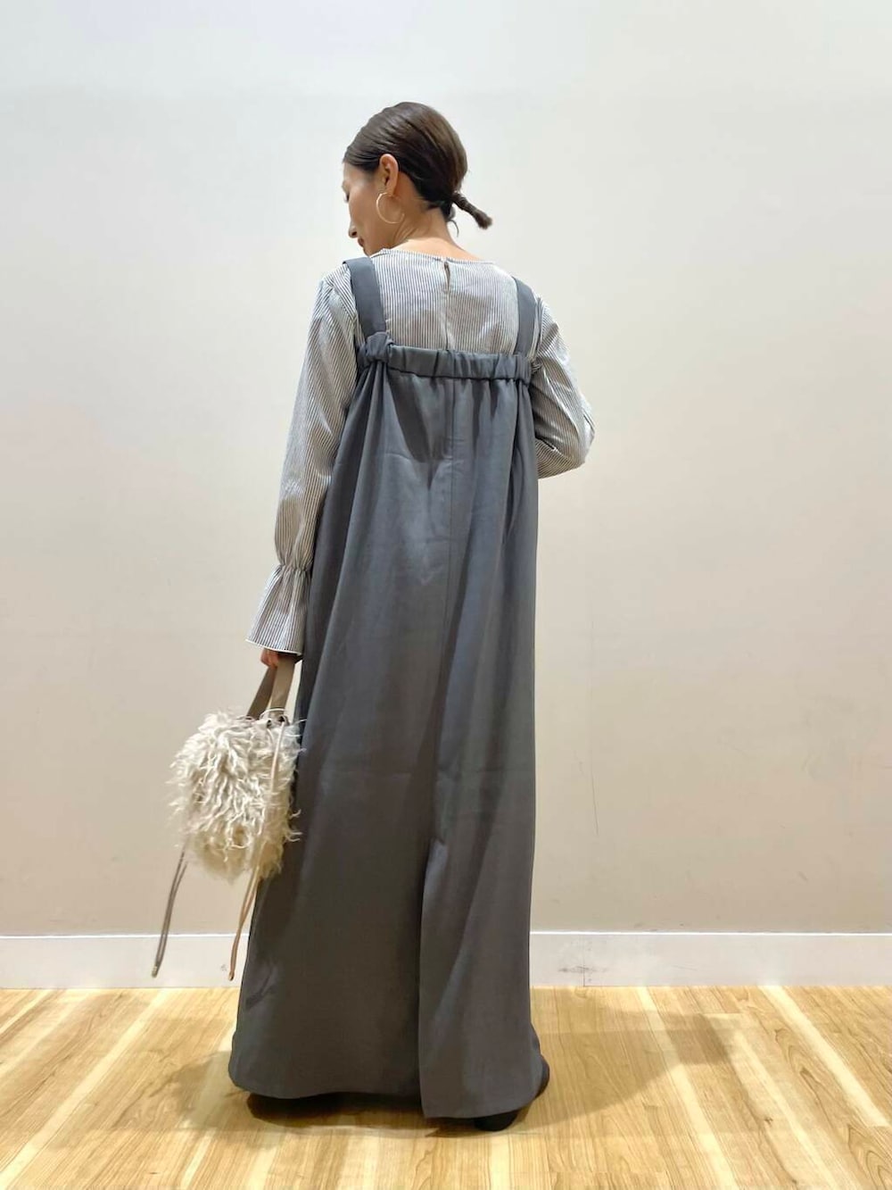 ベージュ系のショルダーバッグ、グレー系のジャンパースカートを着用したレディースの秋コーディネートの4枚目の写真