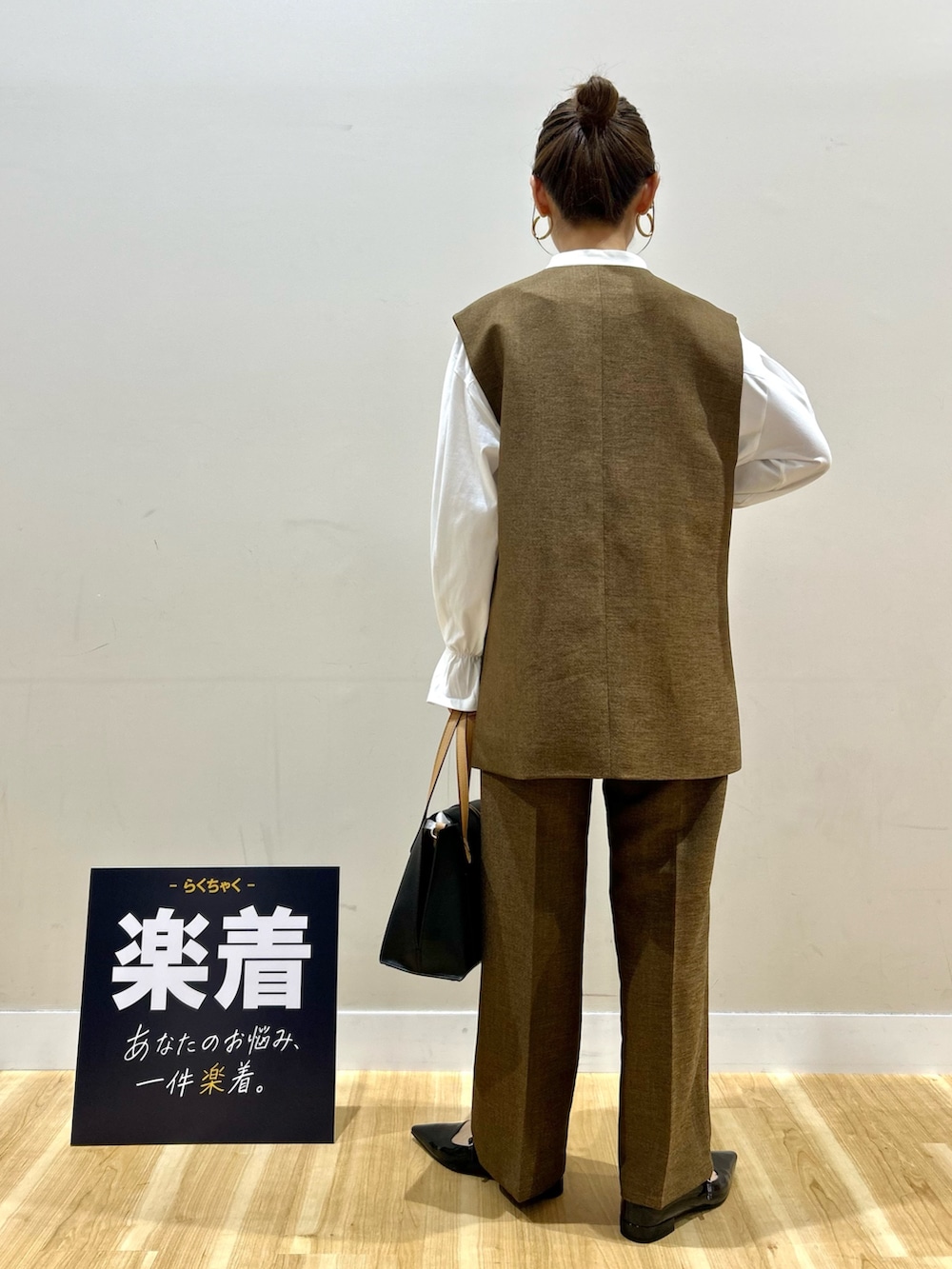 ブラウン系のセットアップ、ホワイト系のシャツ/ブラウス、ブラック系のトートバッグを着用したレディースの春コーディネートの3枚目の写真