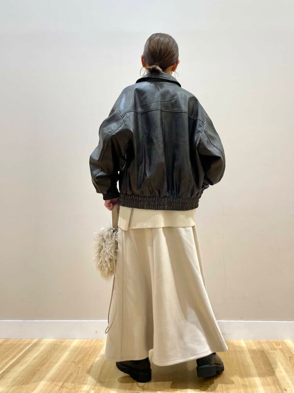 ブラック系のブーツ、ベージュ系のショルダーバッグ、ベージュ系のスカートを着用したレディースの秋コーディネートの3枚目の写真