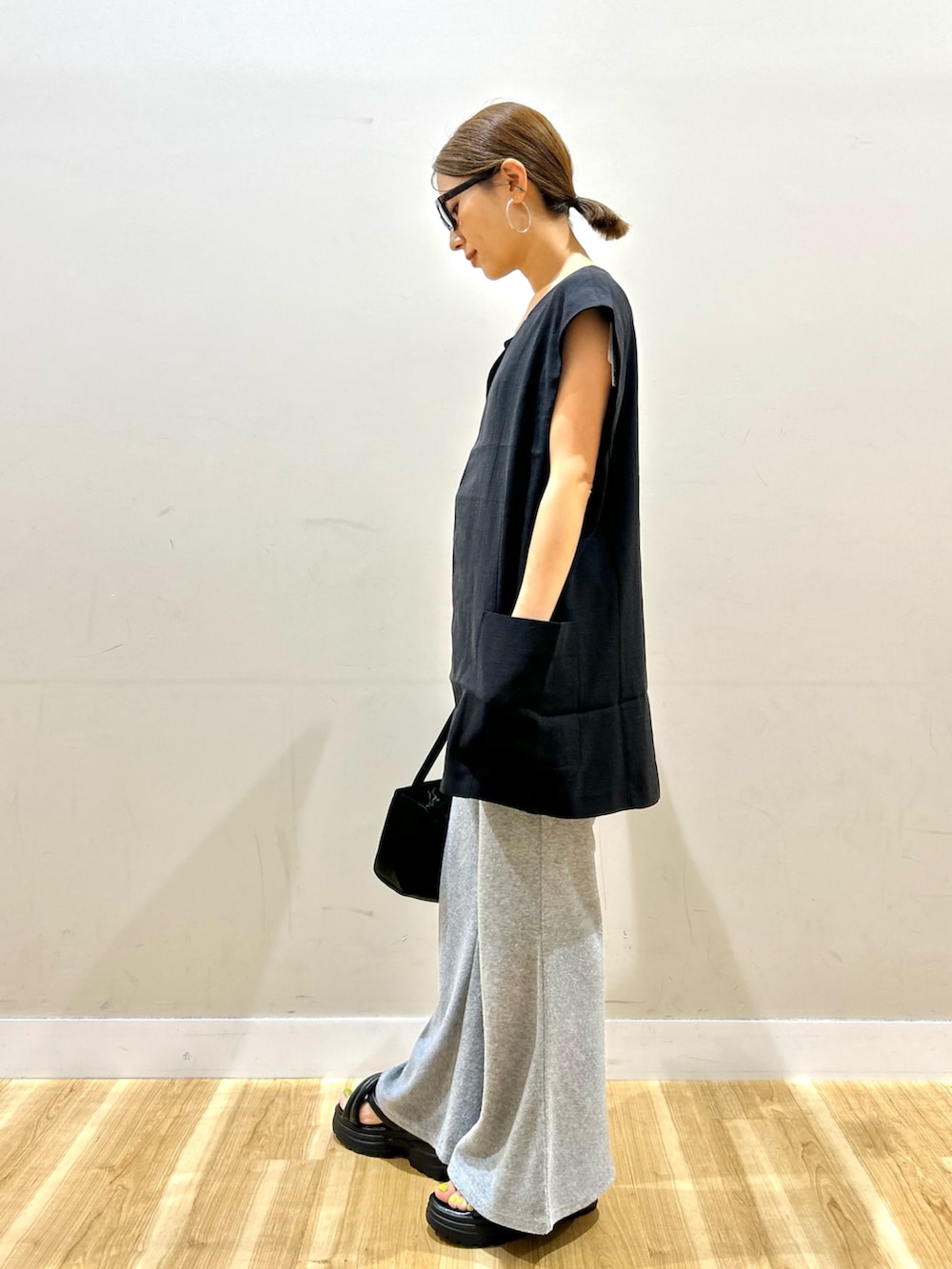 ブラック系のダウンベスト、グレー系のその他パンツ、ブラック系のトートバッグを着用したレディースの夏コーディネートの3枚目の写真