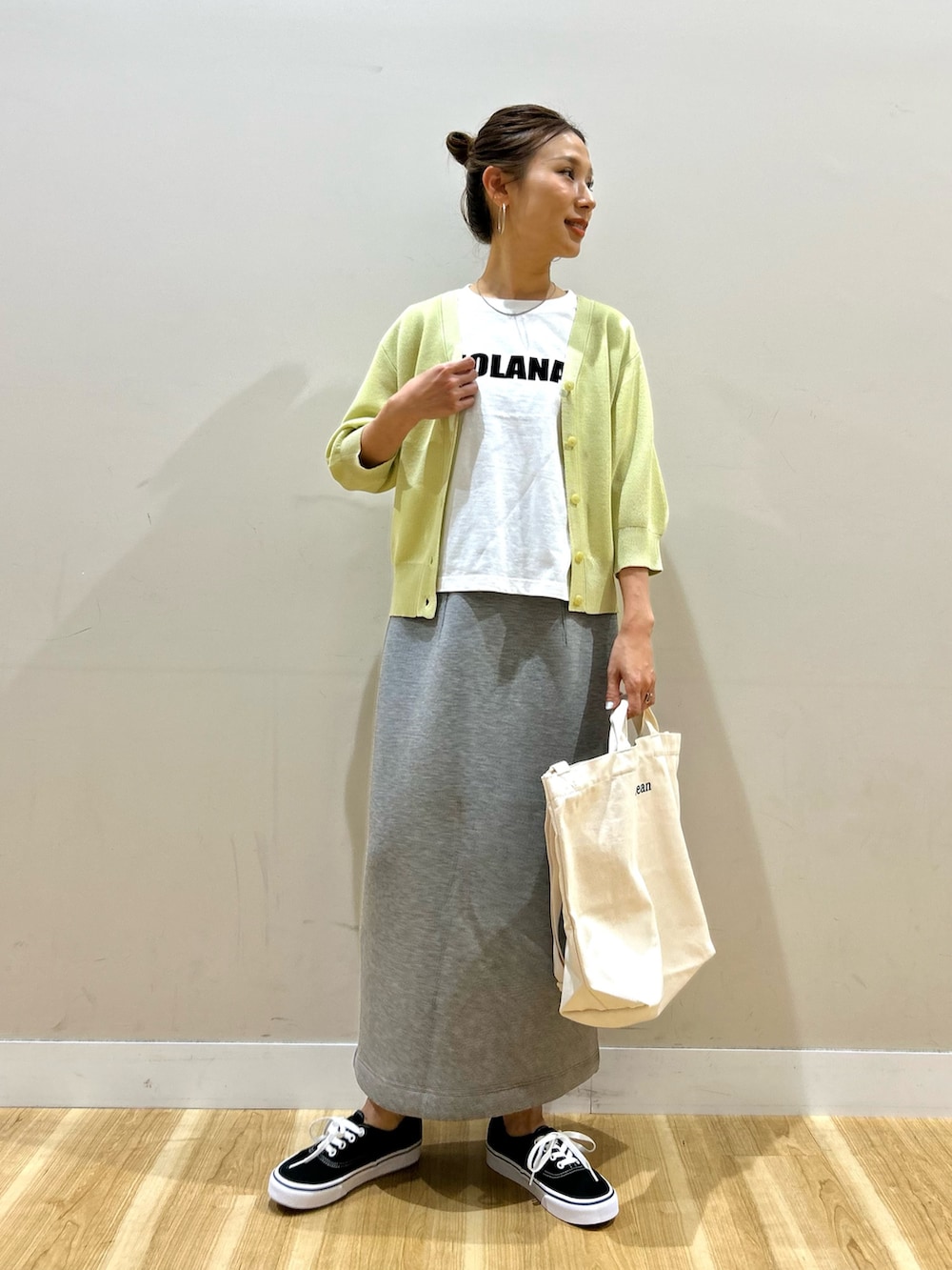 イエロー系のカーディガン/ボレロ、ホワイト系のTシャツ/カットソー、グレー系のスカートを着用したレディースの春コーディネートの7枚目の写真
