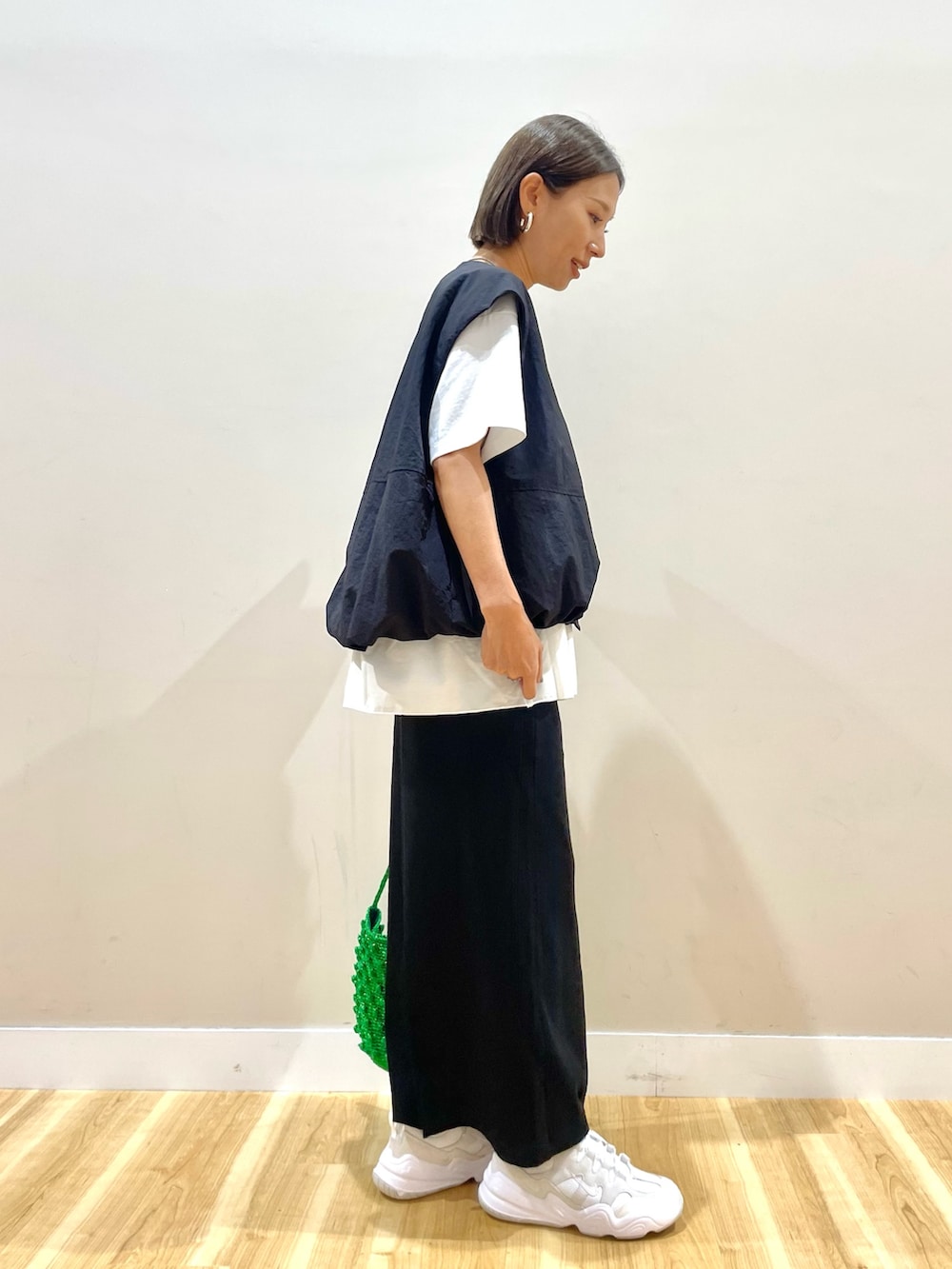 ブラック系のベスト、ホワイト系のTシャツ/カットソー、ブラック系のスカートを着用したレディースの秋コーディネートの4枚目の写真