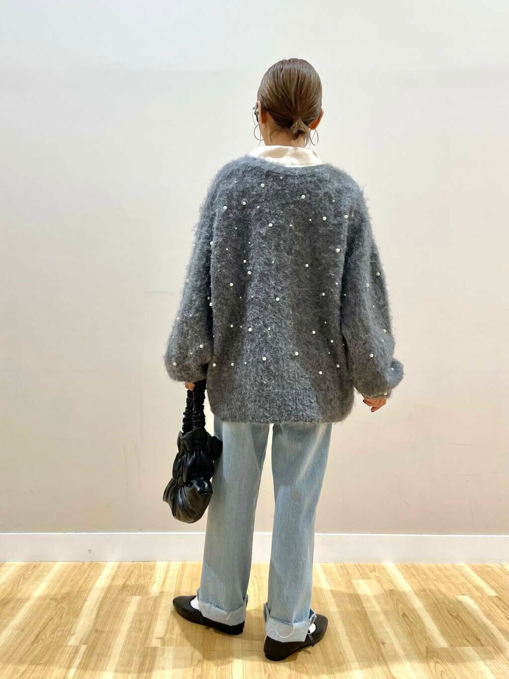 ブラック系のパンプス、ブラック系のハンドバッグ、ブルー系のデニムパンツを着用したレディースの秋コーディネートの5枚目の写真