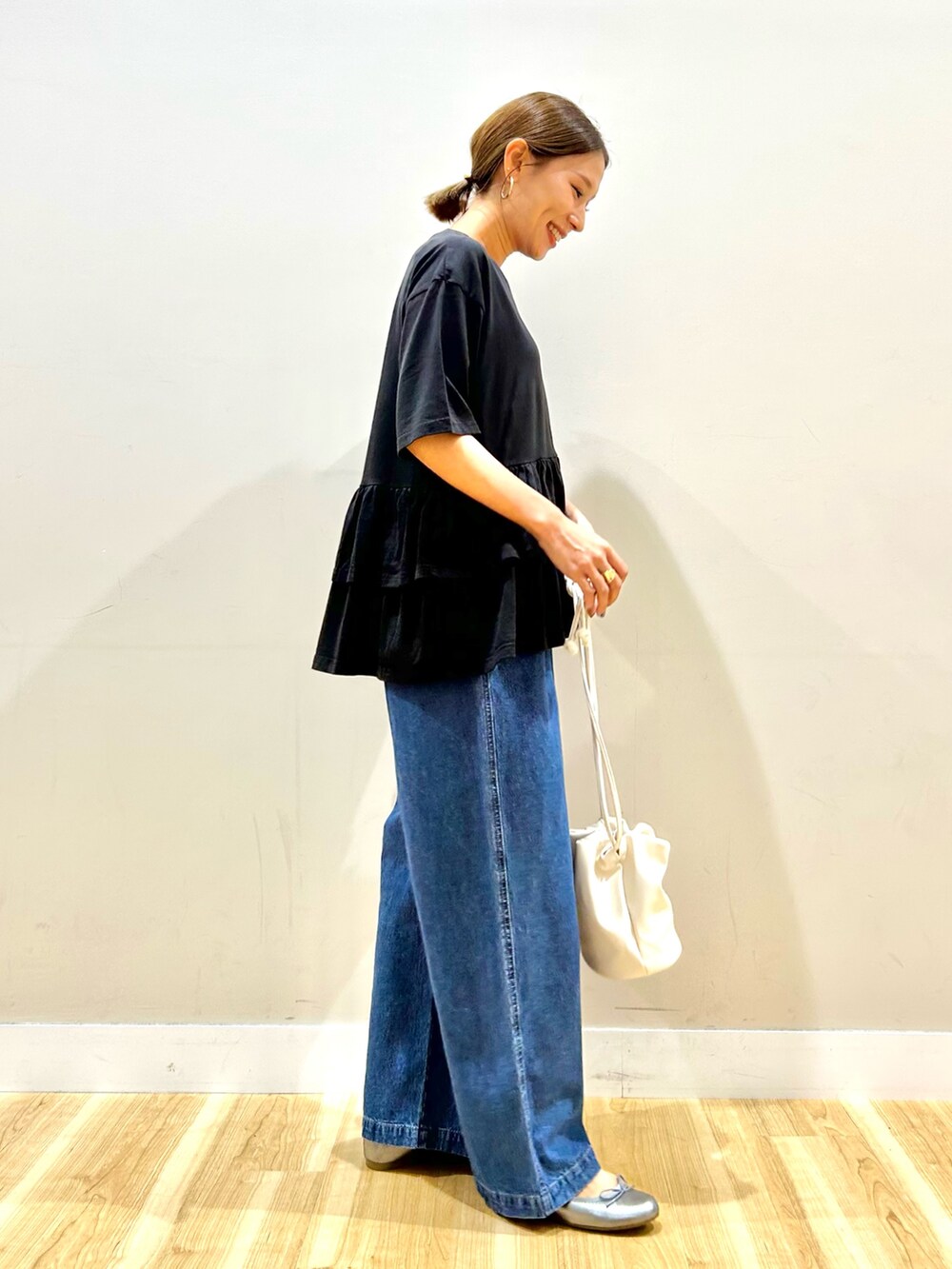 ブラック系のTシャツ/カットソー、ブルー系のデニムパンツ、ゴールド系のショルダーバッグを着用したレディースの秋コーディネートの2枚目の写真