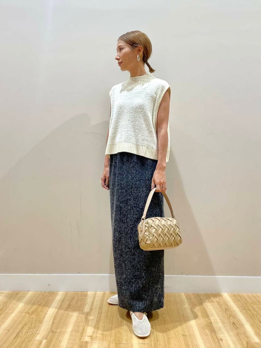 ベージュ系のショルダーバッグ、ブラック系のスカート、ホワイト系のニット/セーターを着用したレディースの夏コーディネートの5枚目の写真