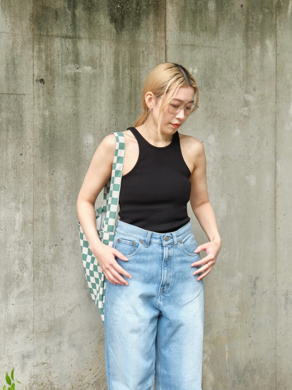 ブラック系のタンクトップ、グリーン系のエコバッグ/サブバッグ、ブルー系のデニムパンツを着用したレディースの夏コーディネートの2枚目の写真