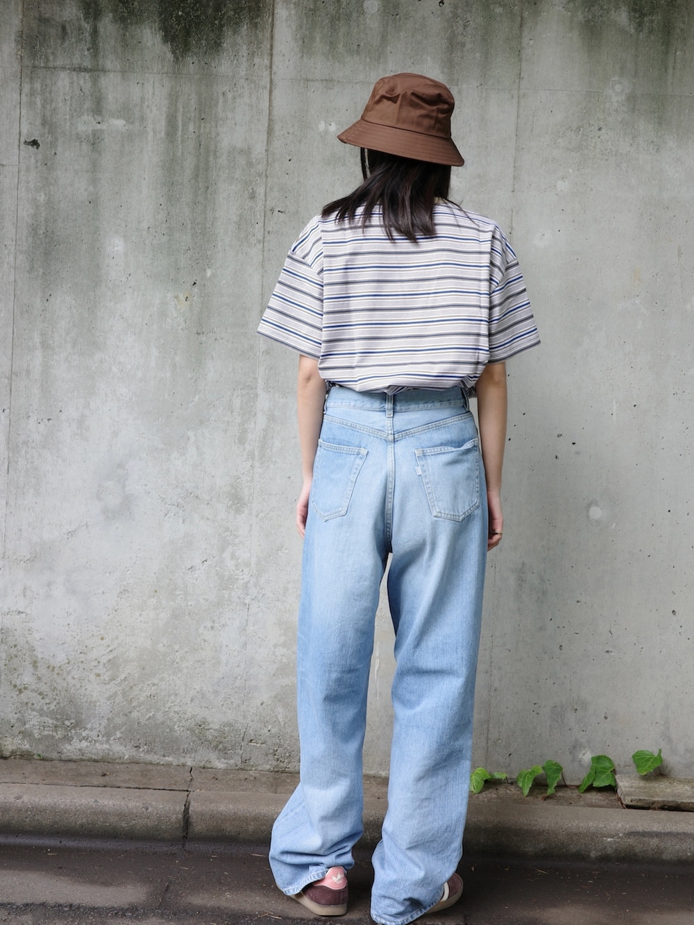 ブルー系のデニムパンツ、ベージュ系のTシャツ/カットソー、ブラウン系のハットを着用したレディースの夏コーディネートの2枚目の写真