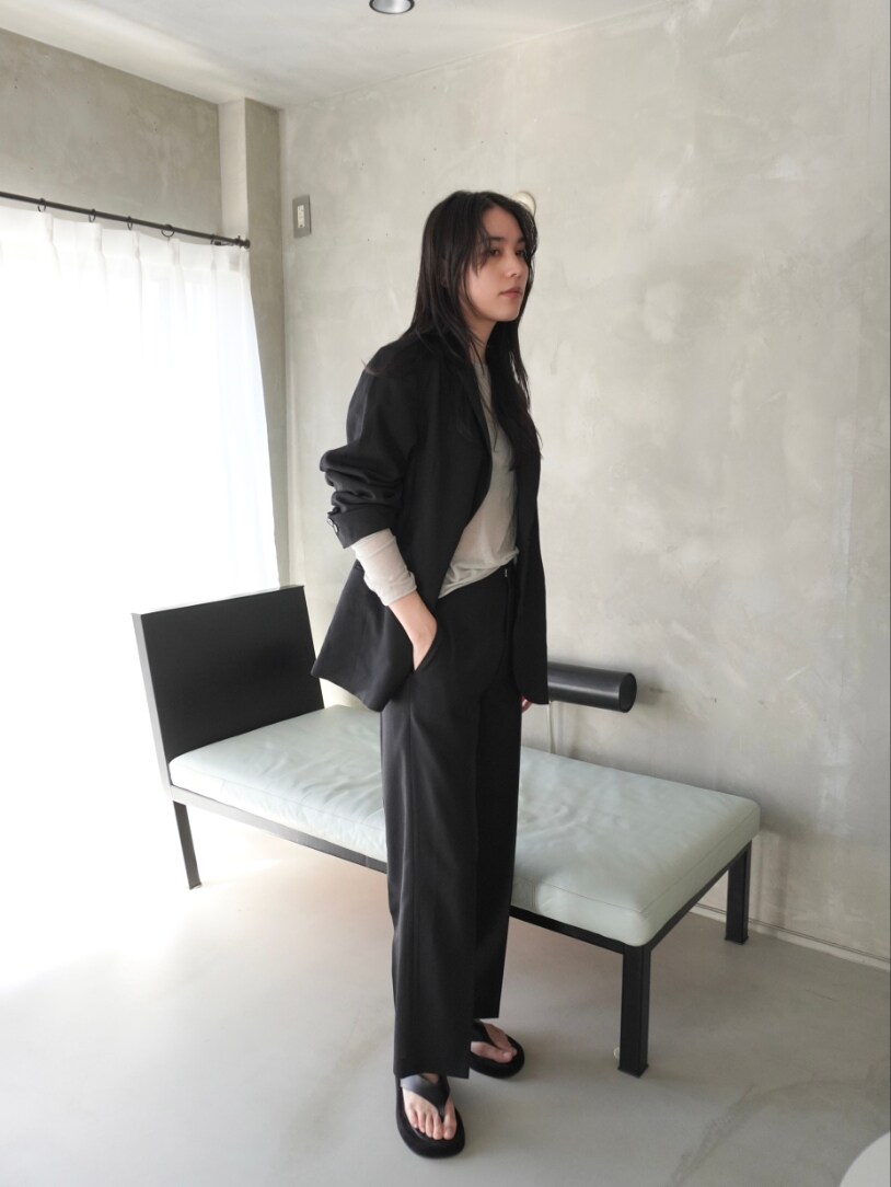 ブラック系のテーラードジャケット、グレー系のTシャツ/カットソー、ブラック系のスラックスを着用したレディースの春コーディネートの2枚目の写真