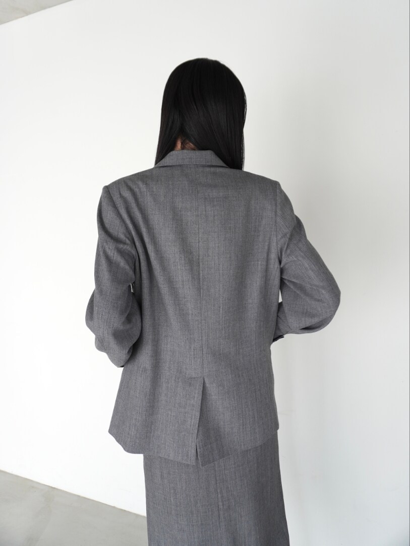 グレー系のスカート、グレー系のテーラードジャケットを着用したレディースの春コーディネートの3枚目の写真