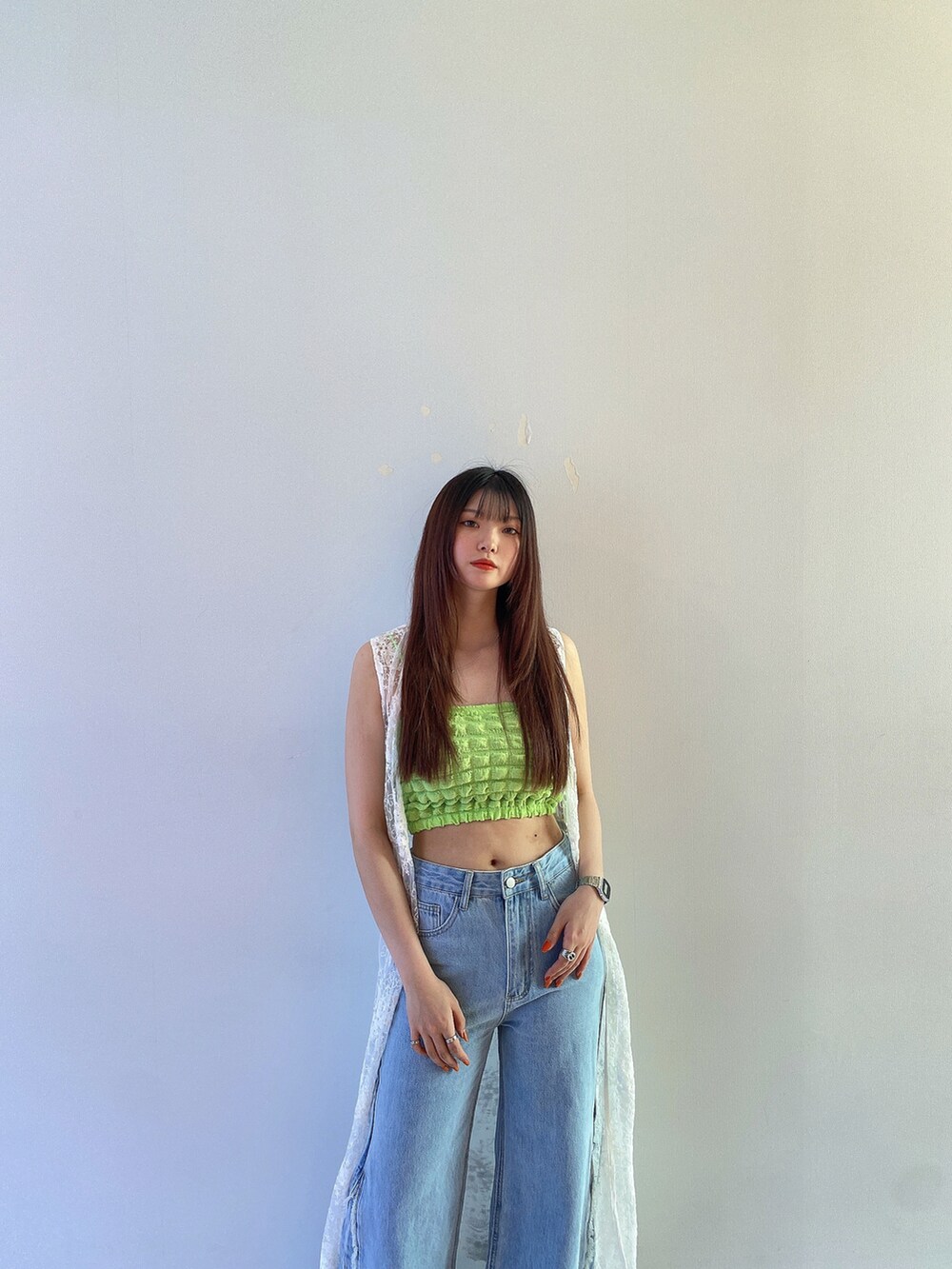 グリーン系のキャミソール、ホワイト系のカーディガン/ボレロ、ブルー系のデニムパンツを着用したレディースの春コーディネートの5枚目の写真