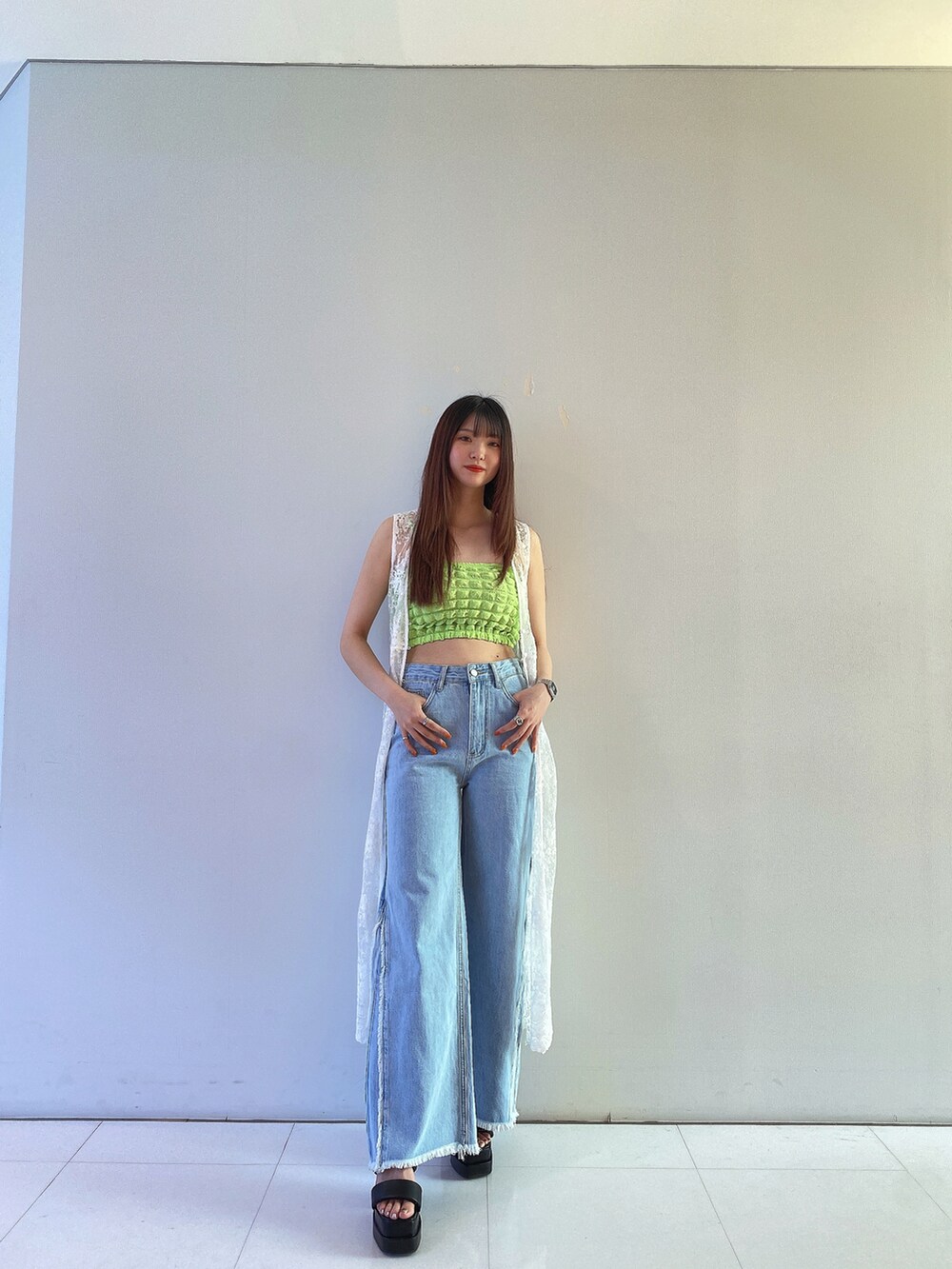グリーン系のキャミソール、ホワイト系のカーディガン/ボレロ、ブルー系のデニムパンツを着用したレディースの春コーディネートの3枚目の写真